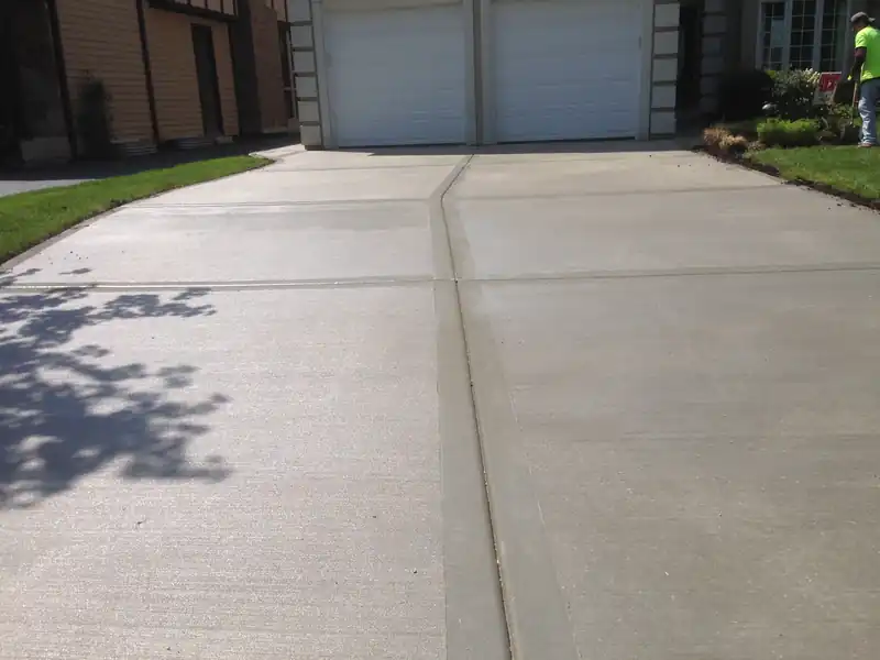 New broom-finished concrete driveway leading to a two-car garage
